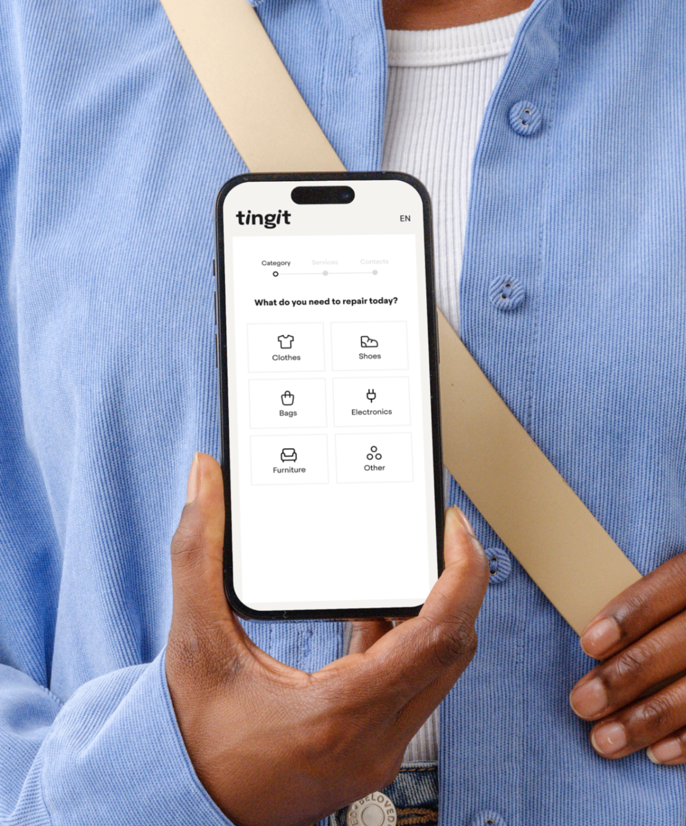 Tingit app on a phone held by a person in a blue cardigan